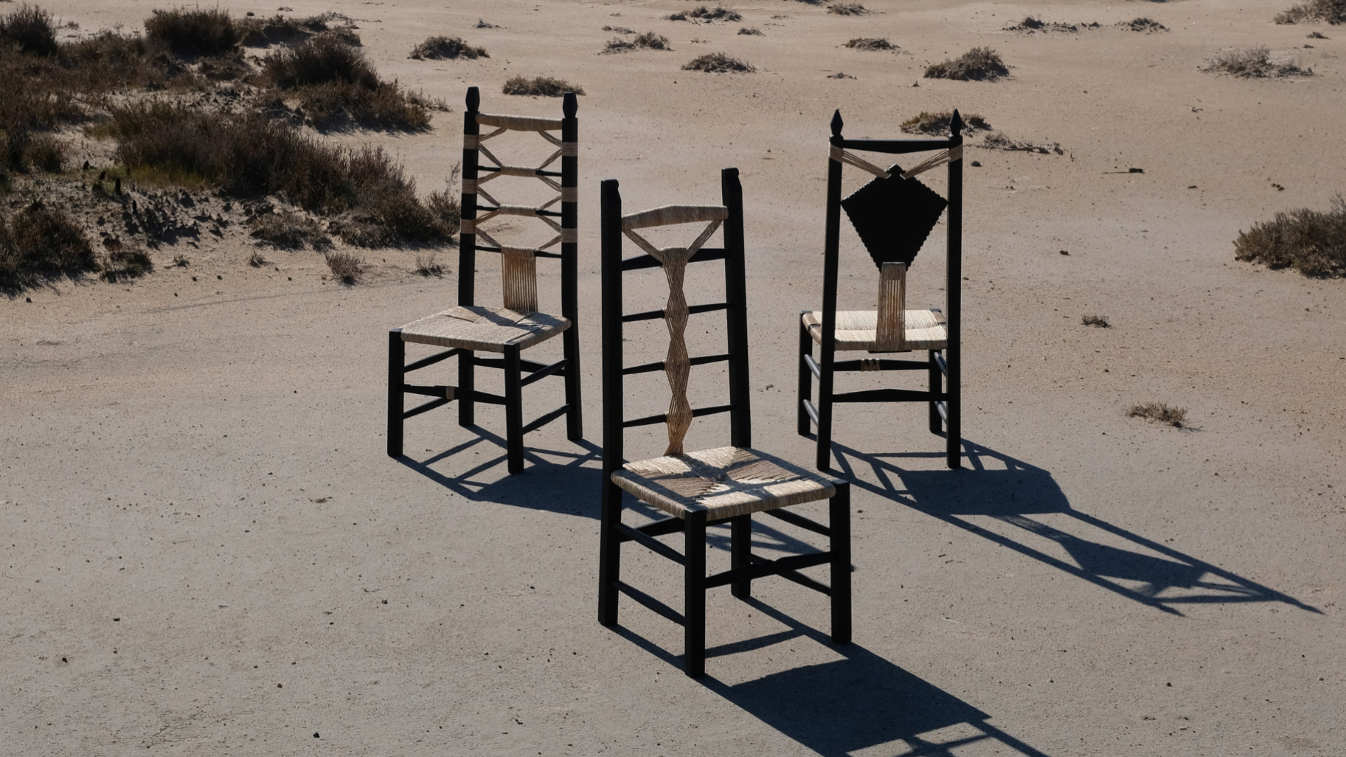 Image of three chairs made from river reed cane and hand carved chestnut wood, shown on a beach landscape in Sardinia.